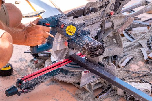 Miter saw. Cutting of PVC profile for siding. Sawdust.