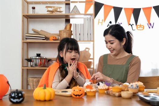 Happy Halloween family mother and daughter getting ready for holiday and baking cookies.