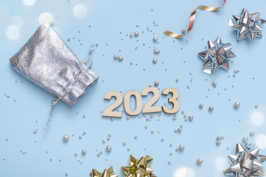 Numbers 2023 on bright festive background with bows and beads top view. Christmas background flat lay.