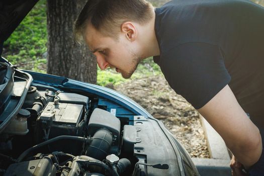 Caucasian man looks at the engine of his car in the hope of identifying a problem.