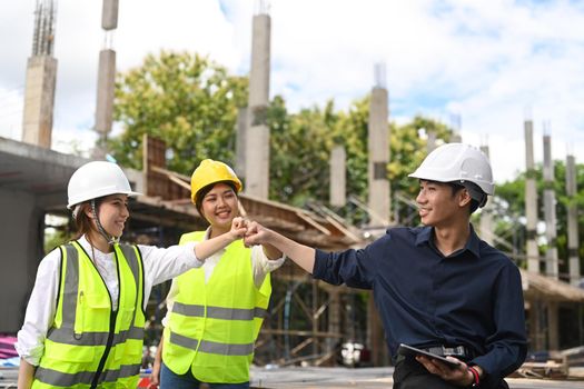 Group of engineer in protective uniform fist bumping hand after complete success project. Industry, Engineer, construction concept.