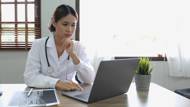 Portrait happy asian woman doctor, Telemedicine concept. Asian female doctor talking with patient using laptop online video webinar consultation while sitting in clinic office.