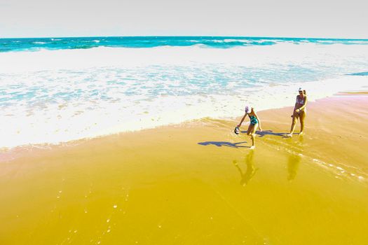 Arenales del Sol, Alicante, Spain- September 18, 2022: Mother and daughter sunbathing and walking by the shore on the beach on a Sunny day of Summer