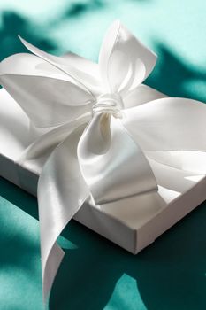 Anniversary celebration, shop sale promotion and bridal surprise concept - Luxury holiday white gift box with silk ribbon and bow on emerald green background, luxe wedding or birthday present