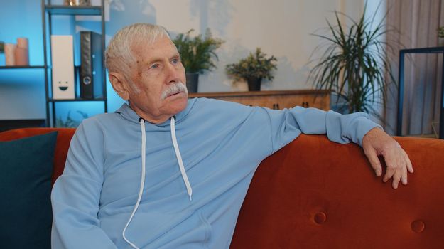 Portrait of sad sick senior old grandfather man at home looks pensive thinks over life concerns or illness, suffers from unfair situation. Problem, break up, depressed feeling bad annoyed, burnout