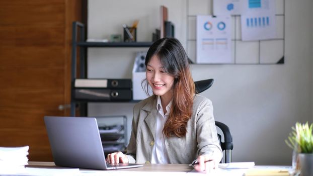 Portrait of smiling beautiful business asian woman working in office use computer with copy space