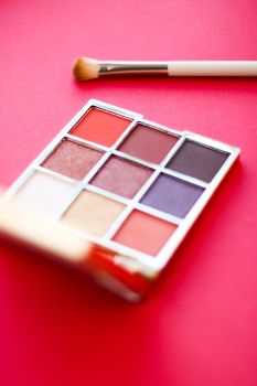 Cosmetic branding, mua and girly concept - Eyeshadow palette and make-up brush on red background, eye shadows cosmetics product for luxury beauty brand promotion and holiday fashion blog design