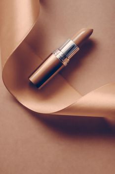 Cosmetic branding, glamour lip gloss and shopping sale concept - Luxury lipstick and silk ribbon on beige holiday background, make-up and cosmetics flatlay for beauty brand product design