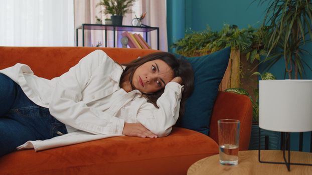 Portrait of sad girl lying at home looks pensive thinks over life concerns or unrequited love, suffers from unfair situation. Young woman problem, break up, depressed feeling bad annoyed, burnout