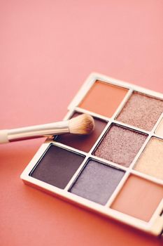 Cosmetic branding, mua and girly concept - Eyeshadow palette and make-up brush on orange background, eye shadows cosmetics product as luxury beauty brand promotion and holiday fashion blog design