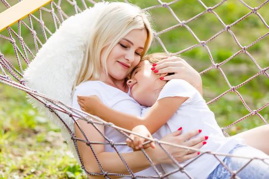 Beautiful young mother with her daughter in forest glade. Happy family relationships. Caucasian woman with baby playing outdoor. Maternal love, caring. Sunshine. Mother's Day