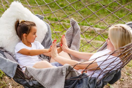happy mother with her daughter lying in a hammock