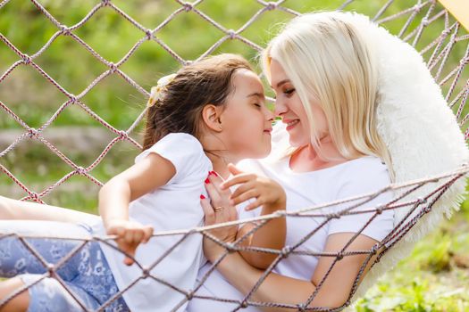 Beautiful young mother with her daughter in forest glade. Happy family relationships. Caucasian woman with baby playing outdoor. Maternal love, caring. Sunshine. Mother's Day