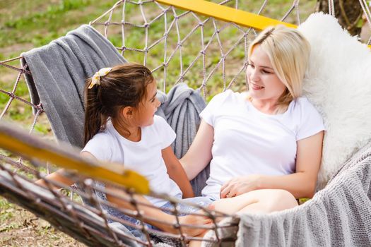 happy mother with her daughter lying in a hammock