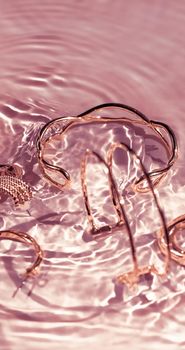 Jewellery branding, fashion gift and luxe shopping concept - Rose gold bracelets, earrings, rings, jewelery on pink water background, luxury glamour and holiday beauty design for jewelry brand ads