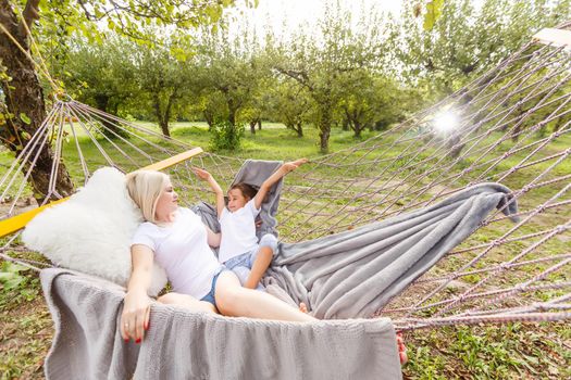 Beautiful young mother with her daughter in forest glade. Happy family relationships. Caucasian woman with baby playing outdoor. Maternal love, caring. Sunshine. Mother's Day