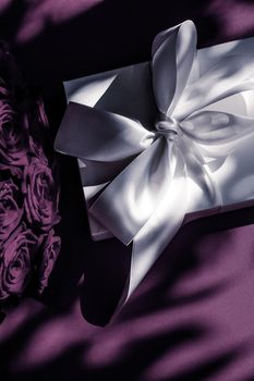 Happy holidays, luxe shopping and love gifts concept - Luxury holiday silk gift box and bouquet of roses on purple background, romantic surprise and flowers as birthday or Valentines Day present