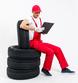 Young mechanic in uniform with a clipboard on white background