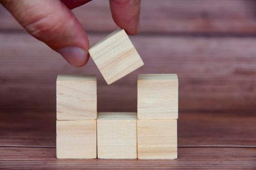 Hand placing wooden block with customizable space for text or ideas. Copy space.