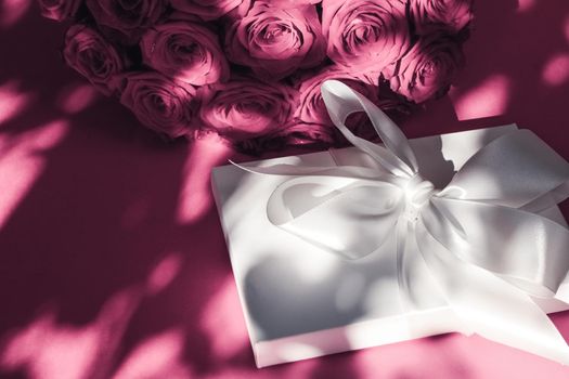 Happy holidays, luxe shopping and love gifts concept - Luxury holiday silk gift box and bouquet of roses on pink background, romantic surprise and flowers as birthday or Valentines Day present