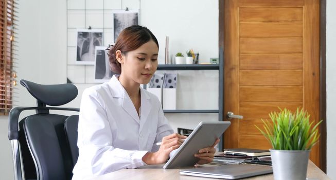 asian female doctor with laptop computer in her office. Friendly medical professional with tablet computer in clinic