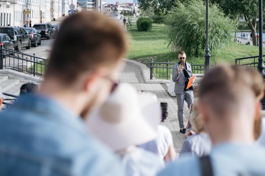 young man is a tour guide telling a group of tourists about local attractions.