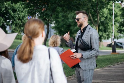 attractive male tour guide inviting a group of tourists on an excursion.