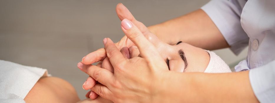 Beautiful caucasian young woman getting a facial massage at a beauty salon