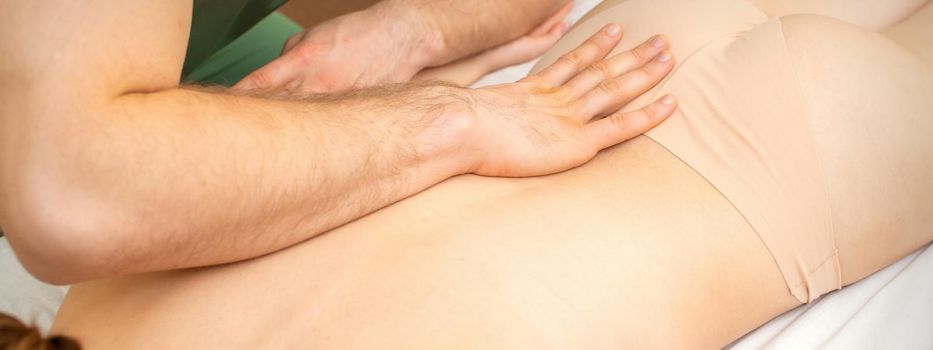 White woman receiving back massage by the hand of a masseur in spa