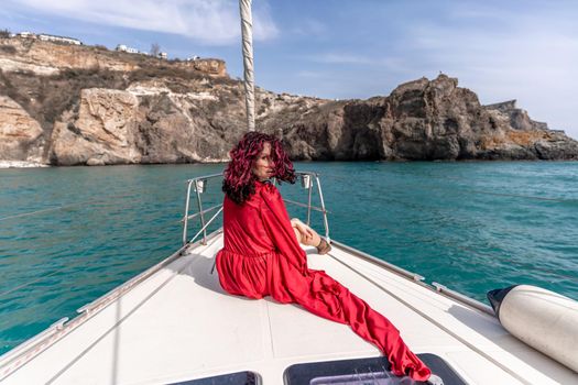 Attractive middle-aged woman in a red dress on a yacht on a summer day. Luxury summer adventure, outdoor activities