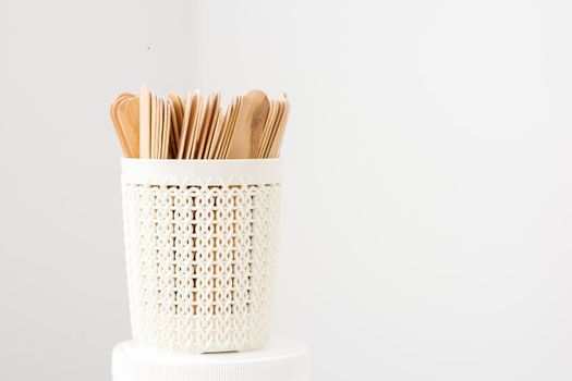 Sticks of wood for wax in white basket isolated on white background with copy space