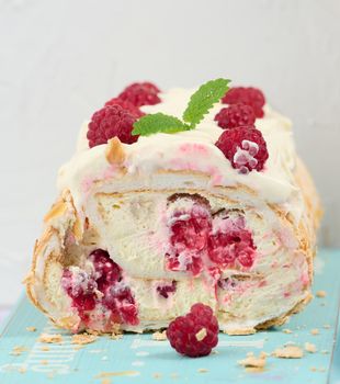 Baked meringue roll with cream and fresh red raspberry, white background	