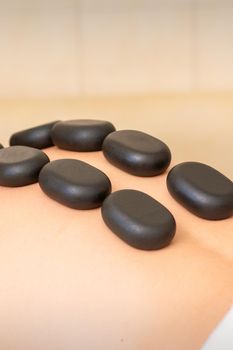 Hot stone massage therapy. Caucasian young man getting a hot stone massage on back at spa salon