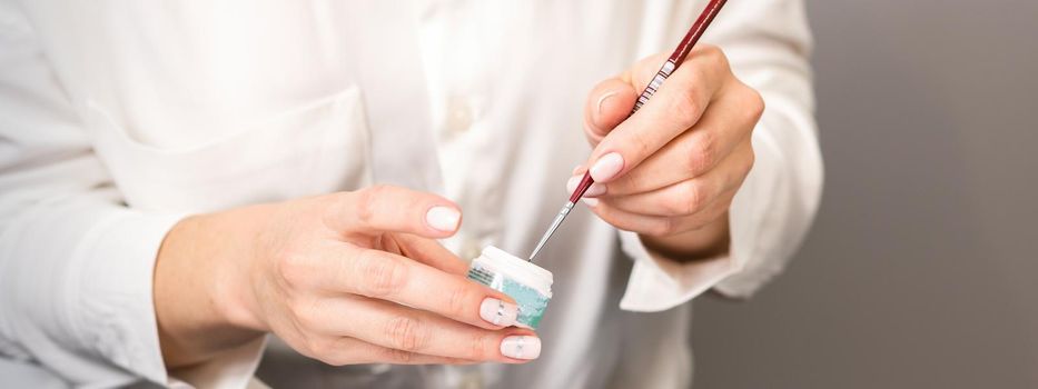 Blue glitter nail polish with a nail brush in hands of female manicurist