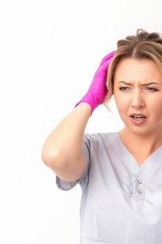 The emotionally shocked young female medical worker holding hands on her head fell into panic on white background, infection, epidemic, virus, and disease concept