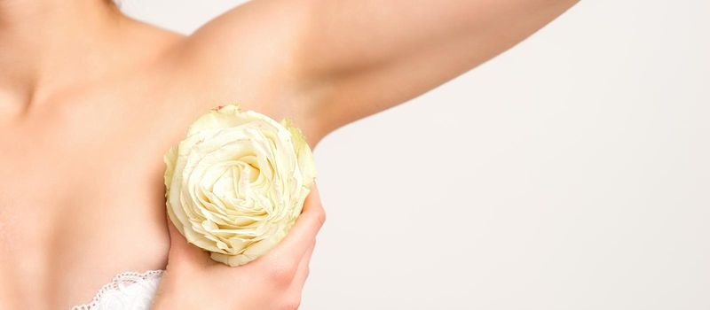 Close up of female armpit with white rose flower isolated on white background