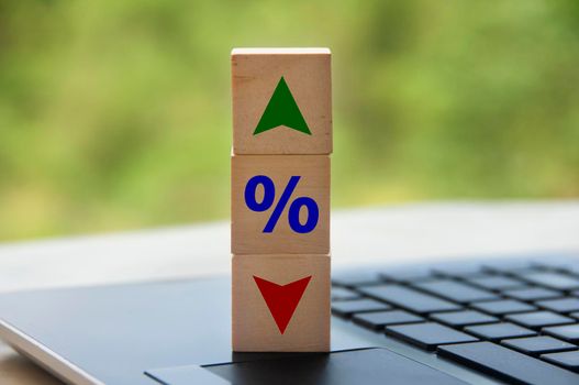 Wooden cube block on laptop keyboard with icon percentage and symbol arrow up and down. Business and Interest fluctuation concept.