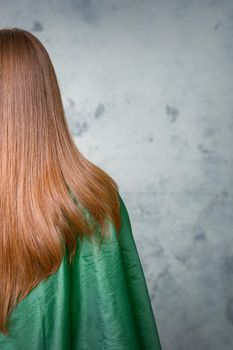 Rear View of a woman with long brown hair against a gray background