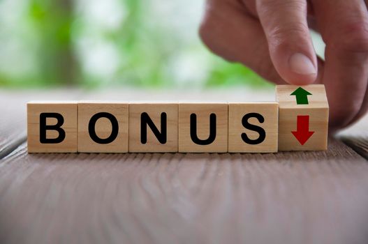 Finger turning wooden block changing the arrow direction up and down for bonus. Salary and bonus increment concept.