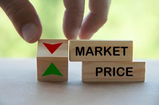 Hand turning direction of arrow on wooden block up and down on market price. Business and market price concept.