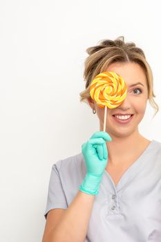 Beautiful smiling beautician holding fresh pineapple and cover her eye with lollipop over white background. Skincare cleansing eco organic
