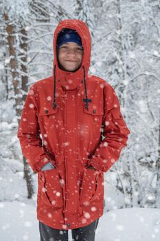 Portrait of teenage boy walking and having fun in winter snowing forest