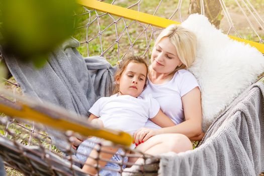 Mother And Daughter Sleeping In Garden Hammock Together