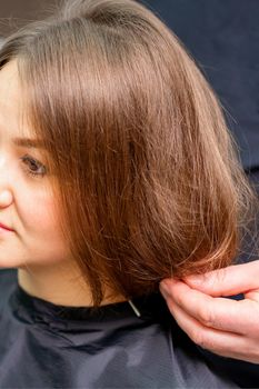 Styling female hair. Male hairdresser makes hairstyle for a young woman in a beauty salon