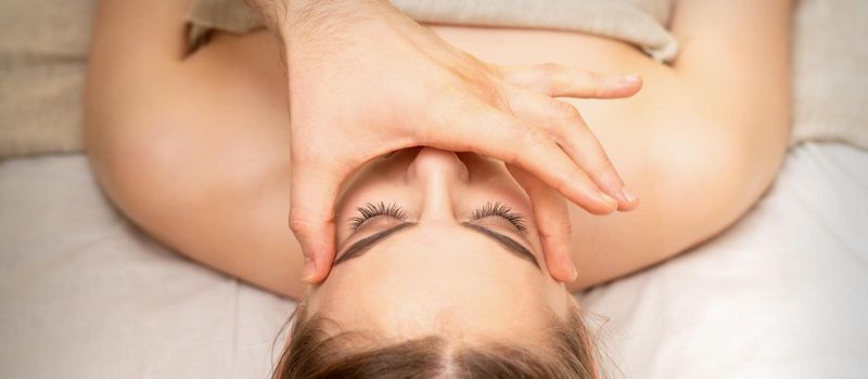 Face massage with fingers of a masseur. Female facial skin care at a beauty spa salon