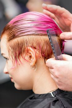 Styling female hair. Male hairdresser makes hairstyle for a young woman in a beauty salon