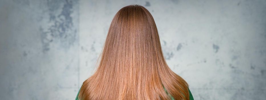 Rear View of a woman with long brown hair against a gray background