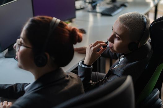 Two women in protective masks are bored at work. Call center operators at the desk.