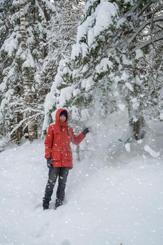 Portrait of teenage boy walking and having fun in winter snowing forest