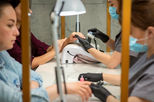 Two women getting a manicure treatment in beauty salon